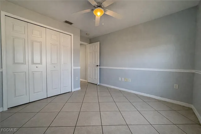a view of an empty room with window and chandelier fan
