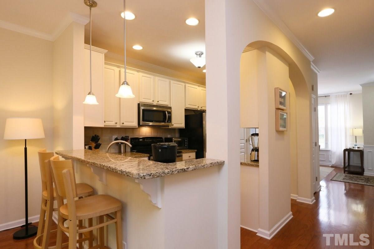226 Cedar Elm Road Durham, NC 27713 - Photo 8 of 25 a kitchen with stainless steel appliances kitchen island granite countertop a stove a sink a refrigerator and a microwave