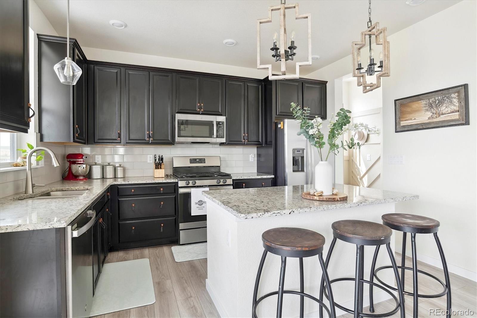 1142 Williams Loop Elizabeth, CO 80107 - Photo 15 of 38 a kitchen with stainless steel appliances granite countertop a kitchen island a stove a sink dishwasher a dining table and chairs with wooden floor