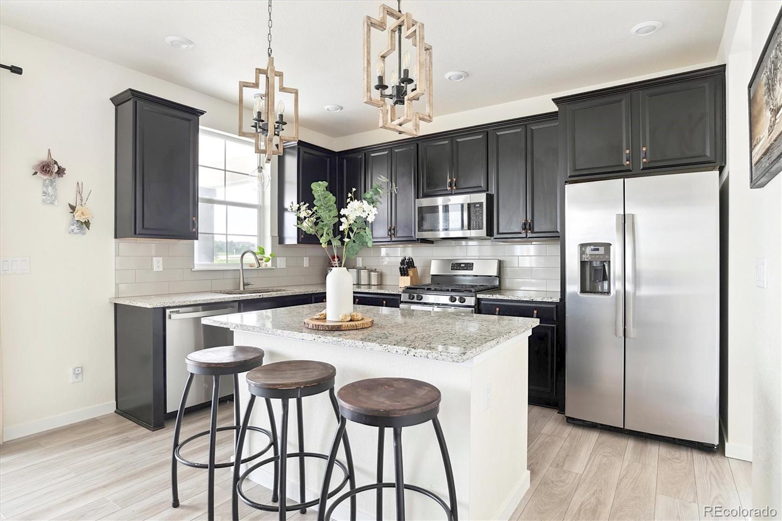 1142 Williams Loop Elizabeth, CO 80107 - Photo 16 of 38 a kitchen with stainless steel appliances granite countertop a kitchen island a stove a refrigerator a sink a dining table and chairs with wooden floor