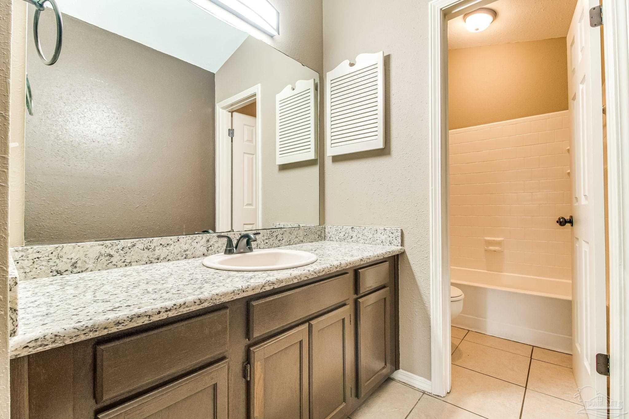 4554 Northpointe Place Pensacola, FL 32514 - Photo 10 of 42 a bathroom with a granite countertop sink and a mirror