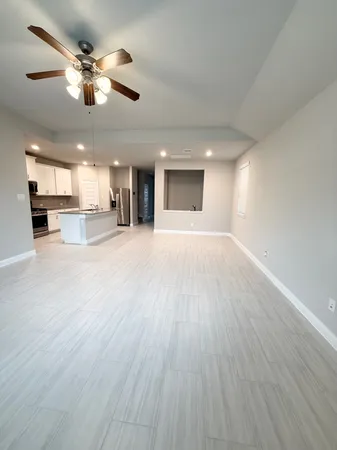 an empty room with wooden floor chandelier and kitchen view