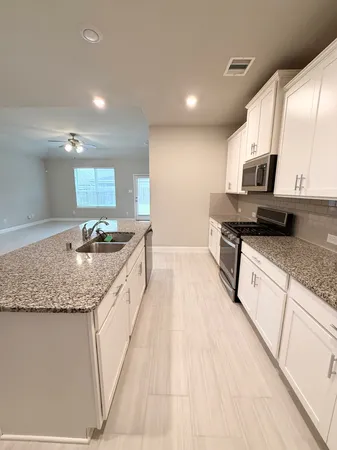 a large kitchen with stainless steel appliances kitchen island granite countertop a sink and cabinets