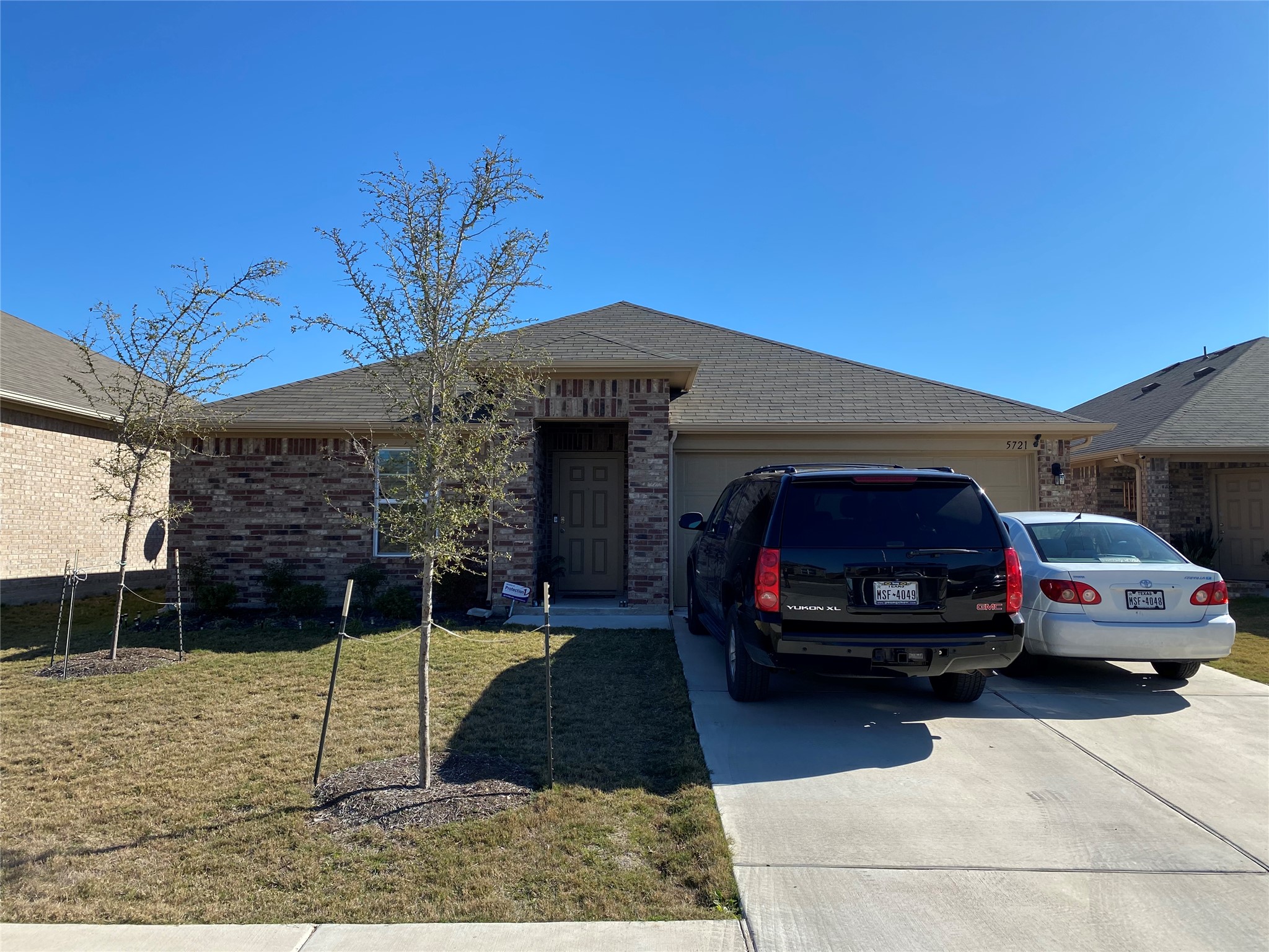 5721 Roderick Drive Austin, TX 78724 - Photo 3 of 26 Single story home featuring a garage, brick siding, driveway, a front lawn, and a shingled roof