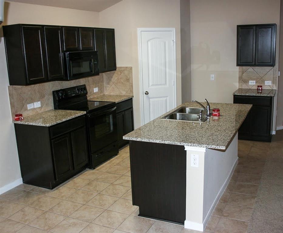5721 Roderick Drive Austin, TX 78724 - Photo 4 of 26 Kitchen with black appliances, backsplash, dark cabinets, light stone counters, and light tile patterned floors