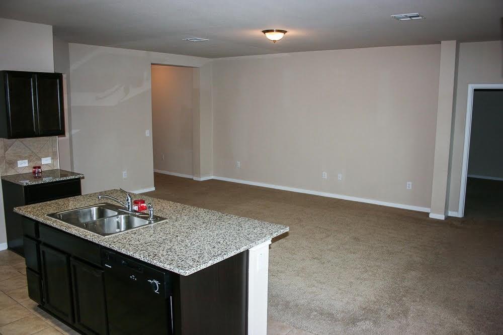 5721 Roderick Drive Austin, TX 78724 - Photo 5 of 26 Kitchen with dark cabinets, a kitchen island with sink, light stone counters, and dishwasher