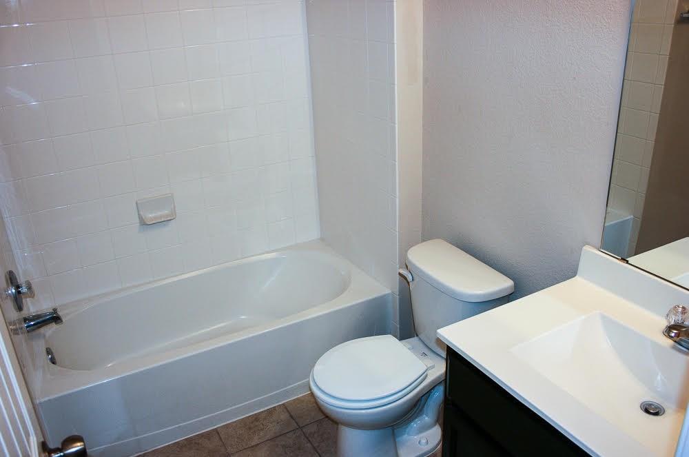 5721 Roderick Drive Austin, TX 78724 - Photo 6 of 26 Full bath featuring vanity, a textured wall, washtub / shower combination, and dark tile patterned flooring