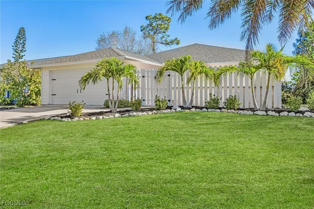 a backyard of a house with table and chairs under an umbrella
