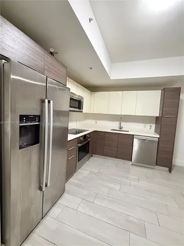 a large white kitchen with a sink and refrigerator