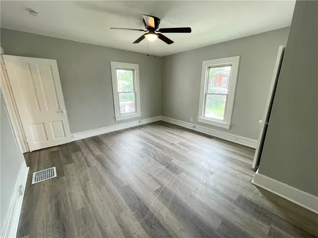 a view of empty room with wooden floor and fan