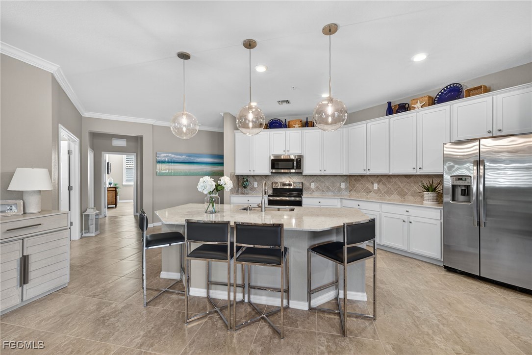 11768 Grand Belvedere Way, Unit 203 Fort Myers, FL 33913 - Photo 10 of 47 a kitchen with kitchen island a dining table chairs a sink and a refrigerator