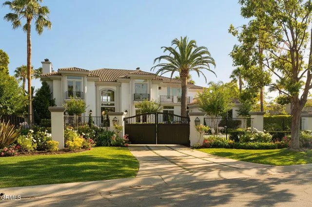 a front view of a house with garden and trees