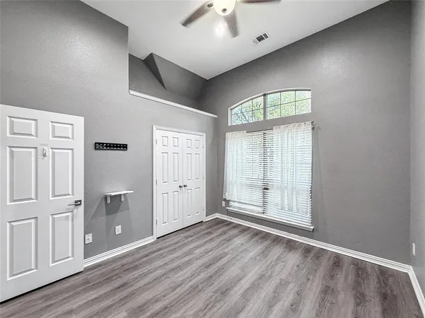 an empty room with wooden floor and windows