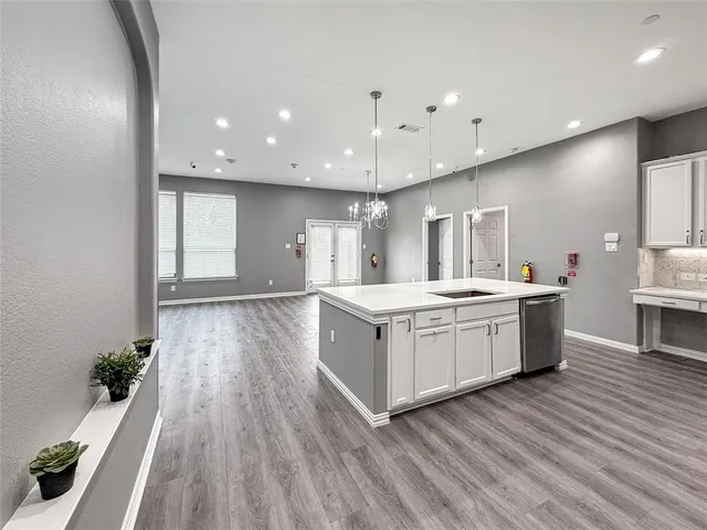 a large kitchen with stainless steel appliances a large counter top and wooden floors