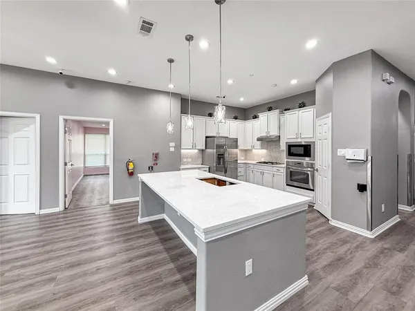 a large room with kitchen island a sink wooden floor and glass doors