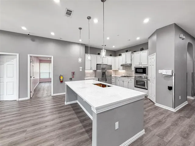a large room with kitchen island a sink wooden floor and glass doors