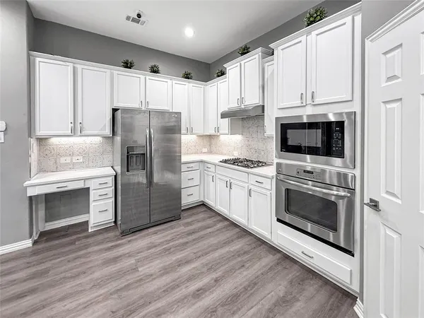 a large kitchen with a large counter top a sink stainless steel appliances and cabinets