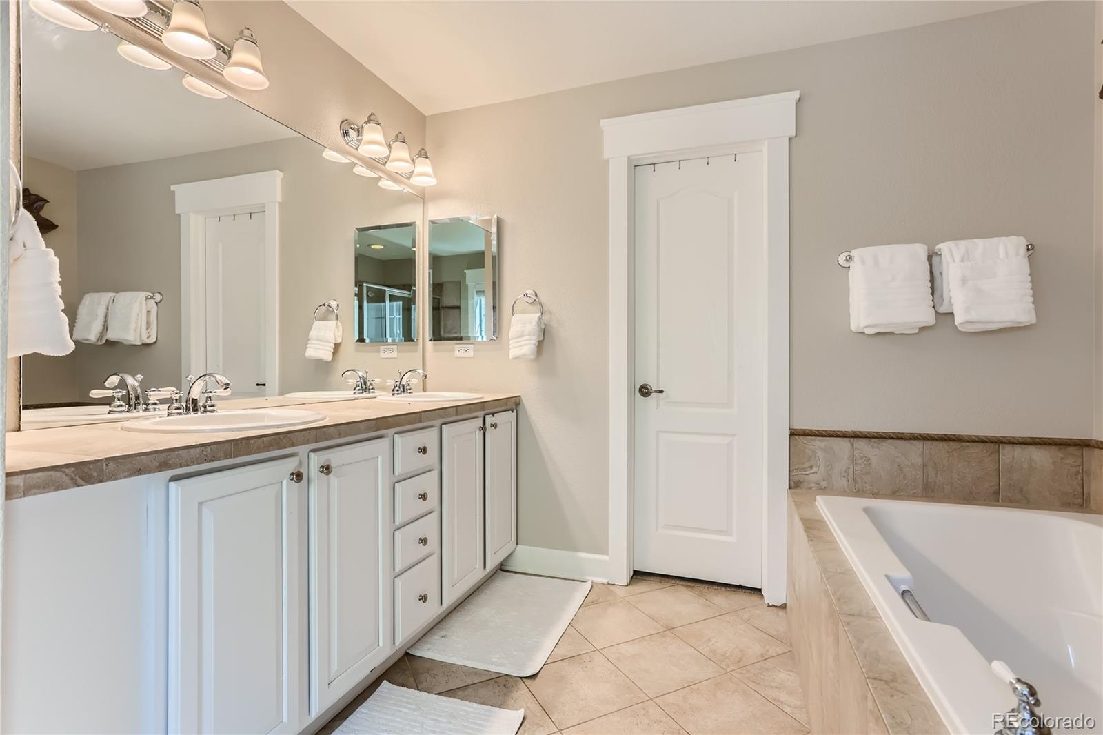 908 Syracuse Street Denver, CO 80230 - Photo 12 of 28 a spacious bathroom with a double vanity sink a large mirror and a bathtub