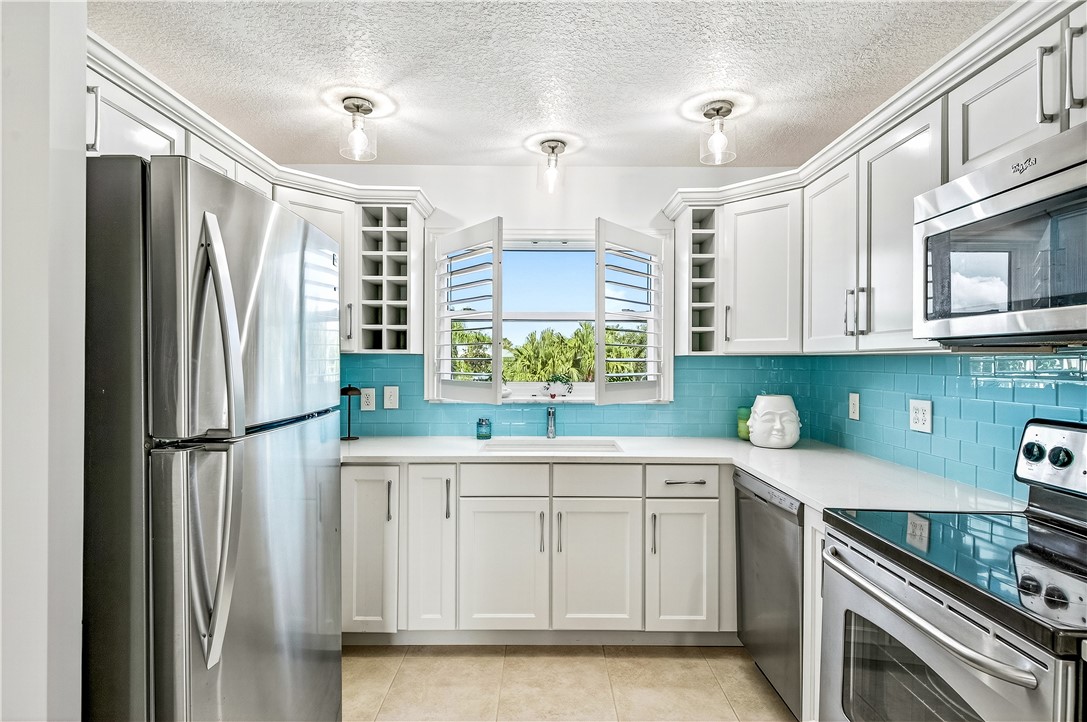 475 Grove Isle Circle, Unit 475 Vero Beach, FL 32962 - Photo 3 of 36 a kitchen with white cabinets and refrigerator