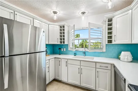 a kitchen with white cabinets white stainless steel appliances and a window