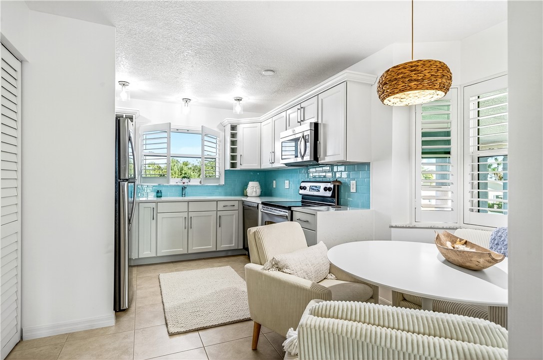 475 Grove Isle Circle, Unit 475 Vero Beach, FL 32962 - Photo 6 of 36 a living room with furniture a chandelier and a table