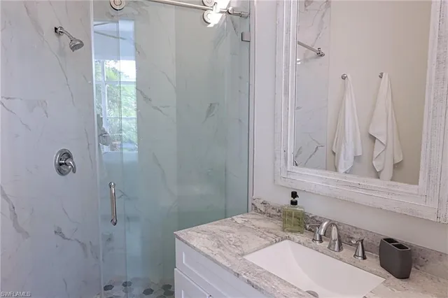 a bathroom with a granite countertop sink a mirror and shower