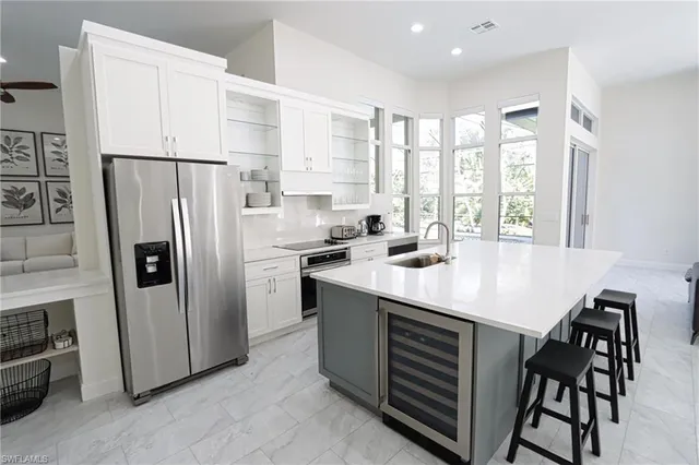 a kitchen with stainless steel appliances a refrigerator a sink a stove and white cabinets