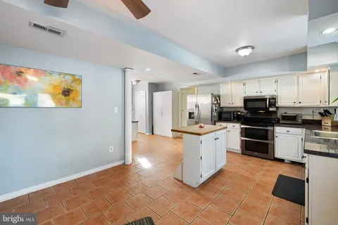 a kitchen with stainless steel appliances granite countertop a stove top oven a sink and a refrigerator