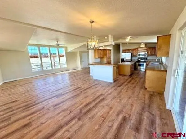 a view of a kitchen with kitchen island a sink wooden floor and a large window
