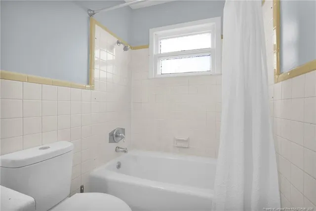 a white bath tub sitting next to a white toilet and a shower