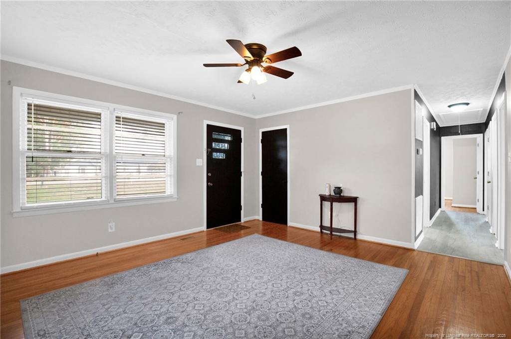 623 Isaac Weeks Road Clinton, NC 28328 - Photo 7 of 24 a workspace with wooden floor a ceiling fan and windows