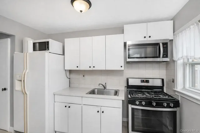 a kitchen with stainless steel appliances granite countertop white cabinets a stove top oven with a sink and dishwasher