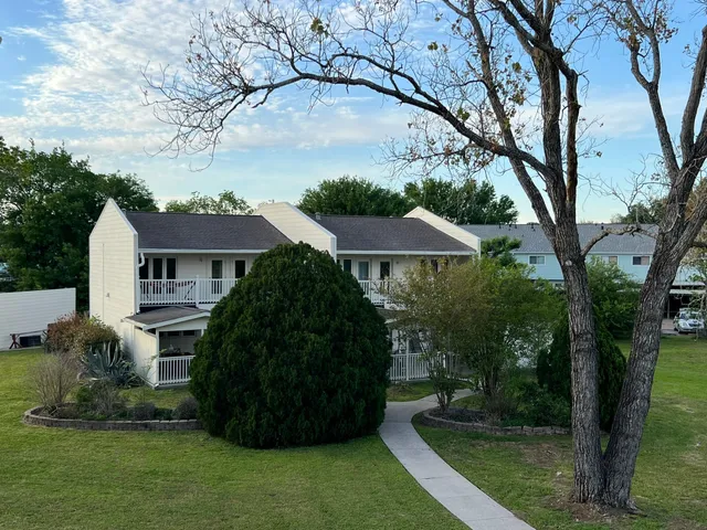 a view of house with garden and tall trees