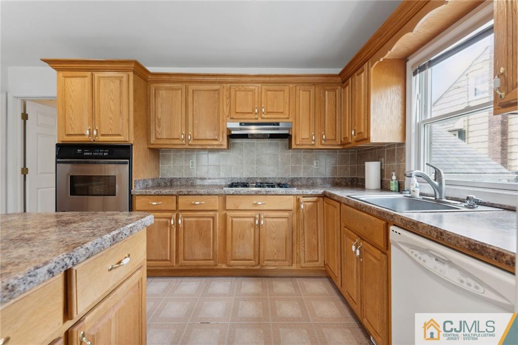 8 Longfellow Drive Colonia, NJ 07067 - Photo 9 of 25 a kitchen with kitchen island granite countertop a sink window and cabinets