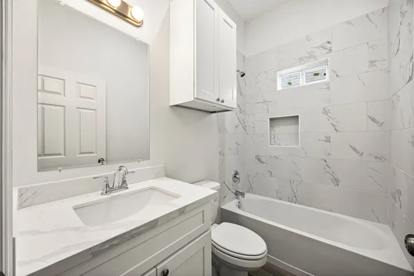 a bathroom with a granite countertop sink a toilet and bathtub