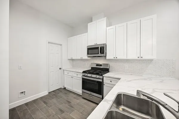a kitchen with granite countertop white cabinets and stainless steel appliances