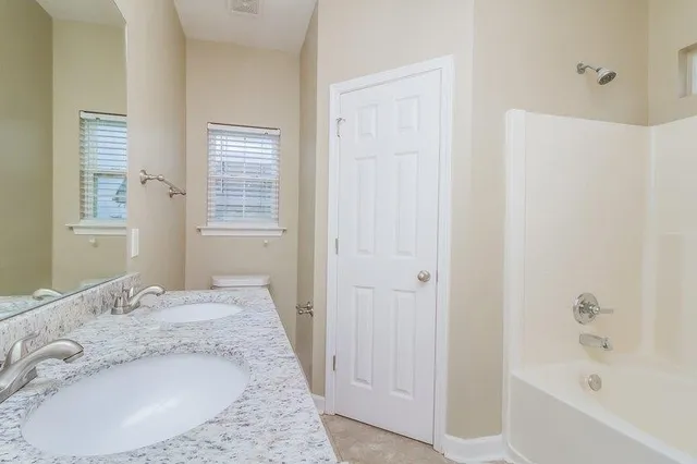 a bathroom with a granite countertop tub sink and mirror