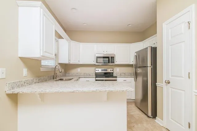 a kitchen with stainless steel appliances granite countertop a refrigerator a stove a sink and a granite counter tops