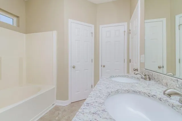 a bathroom with a granite countertop sink and a bathtub
