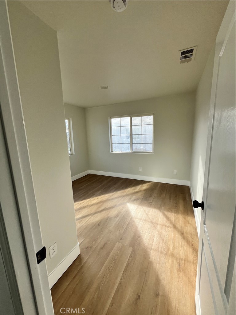 1004 South Riverside Avenue, Unit C1 Rialto, CA 92376 - Photo 11 of 19 an empty room with wooden floor and windows