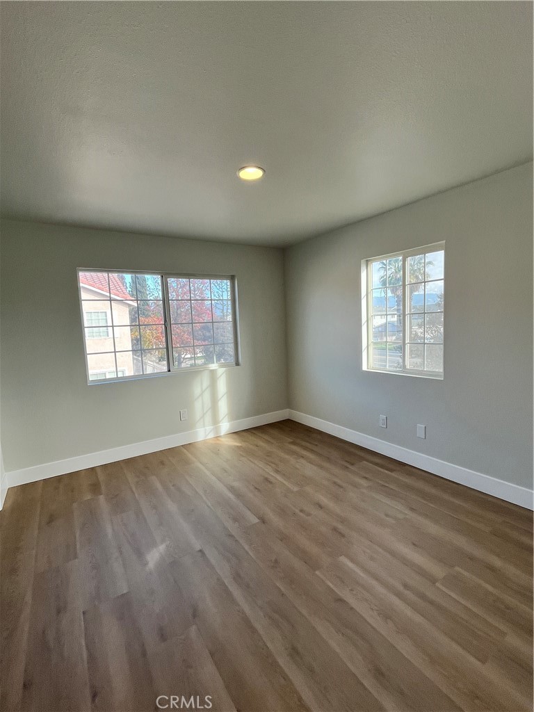 1004 South Riverside Avenue, Unit C1 Rialto, CA 92376 - Photo 17 of 19 an empty room with wooden floor and windows