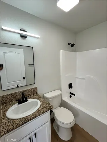 a bathroom with a granite countertop toilet a sink and a mirror