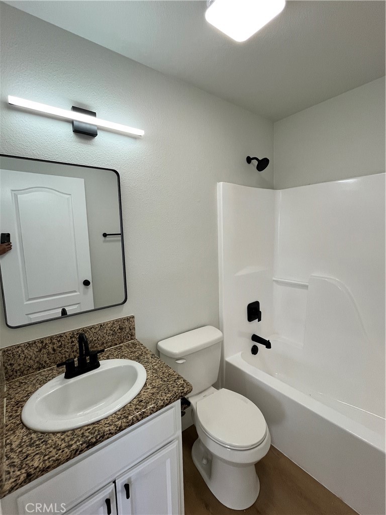 1004 South Riverside Avenue, Unit C1 Rialto, CA 92376 - Photo 18 of 19 a bathroom with a granite countertop toilet a sink and a mirror