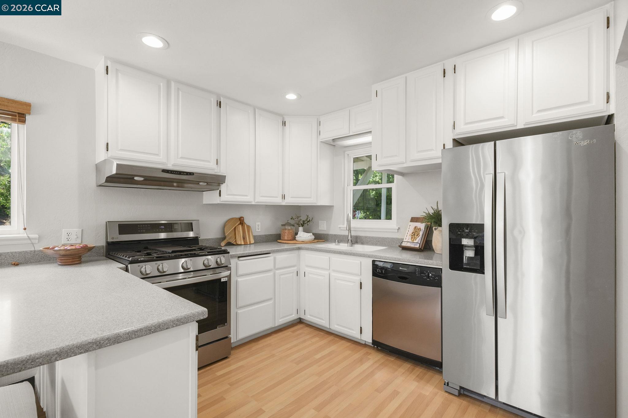 4311 Cowell Road Concord, CA 94521 - Photo 14 of 29 a kitchen with stainless steel appliances granite countertop a refrigerator a sink dishwasher a stove and white countertops with wooden floor