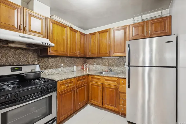 a kitchen with stainless steel appliances granite countertop a refrigerator stove sink and cabinets