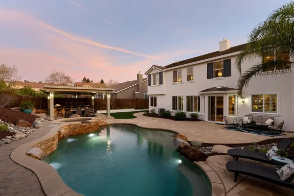 a view of a house with backyard water fountain and sitting area
