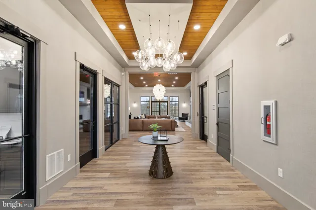 a view of a hallway view with wooden floor and chandelier
