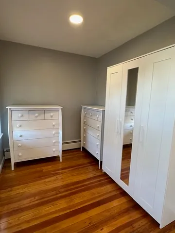 a view of an empty room with wooden floor and closet