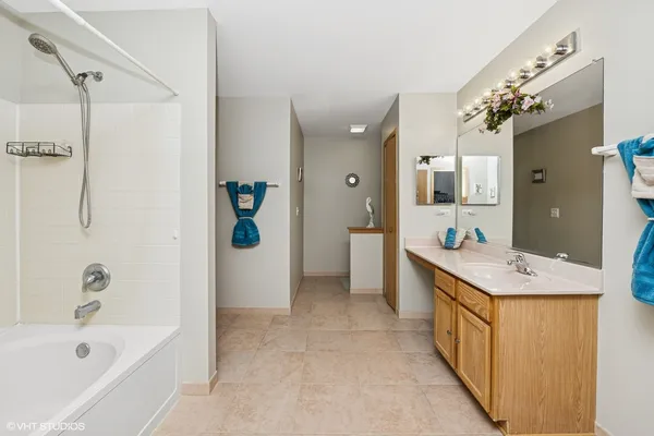 a bathroom with a sink a granite tub shower and mirror