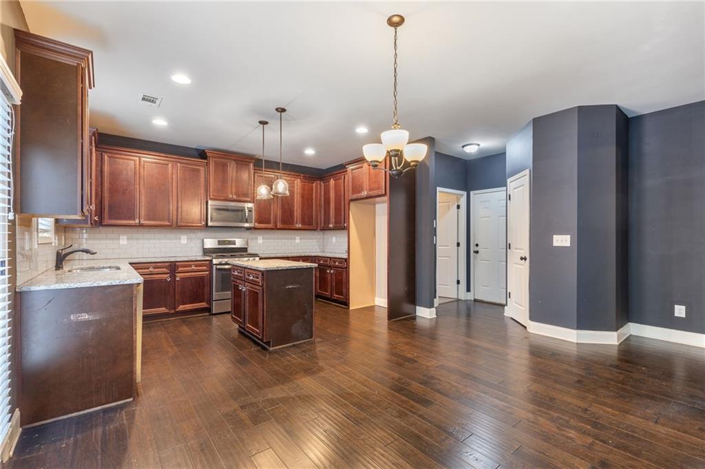 1023 Ruddy Duck Drive Jefferson, GA 30549 - Photo 17 of 69 a open kitchen with stainless steel appliances granite countertop a refrigerator a sink dishwasher a stove and white countertops with wooden floor